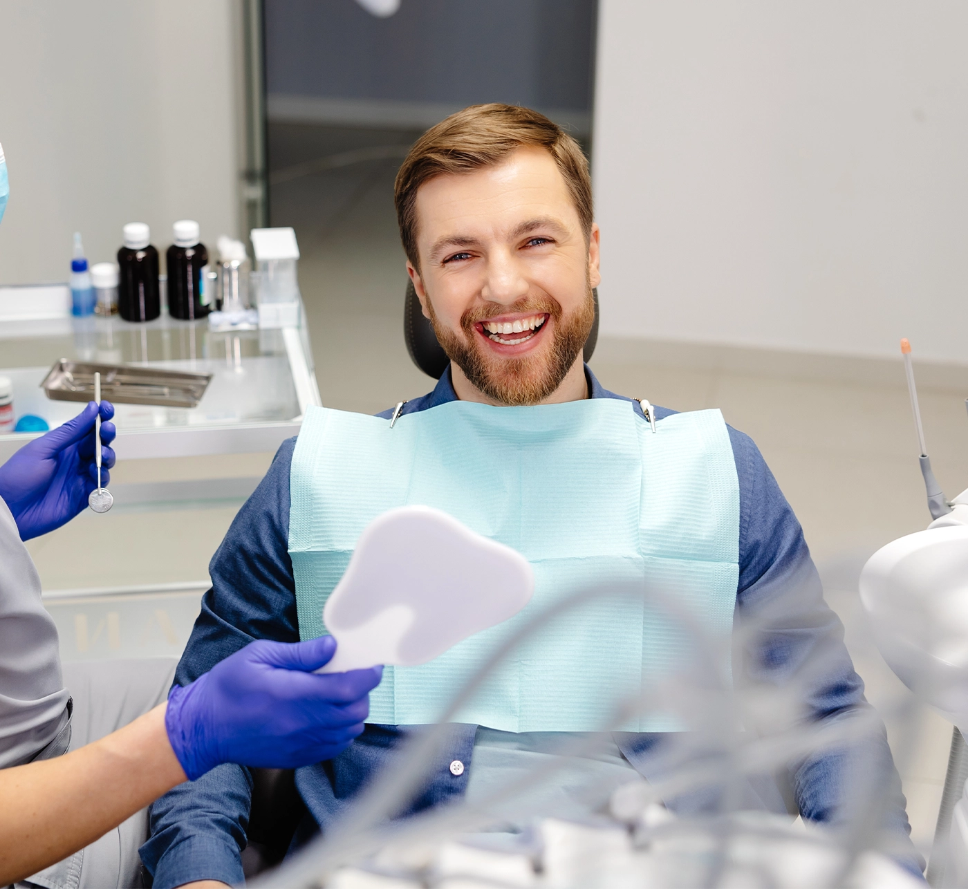 Handsome male patient looking at his beautiful smile sitting at the dental office.