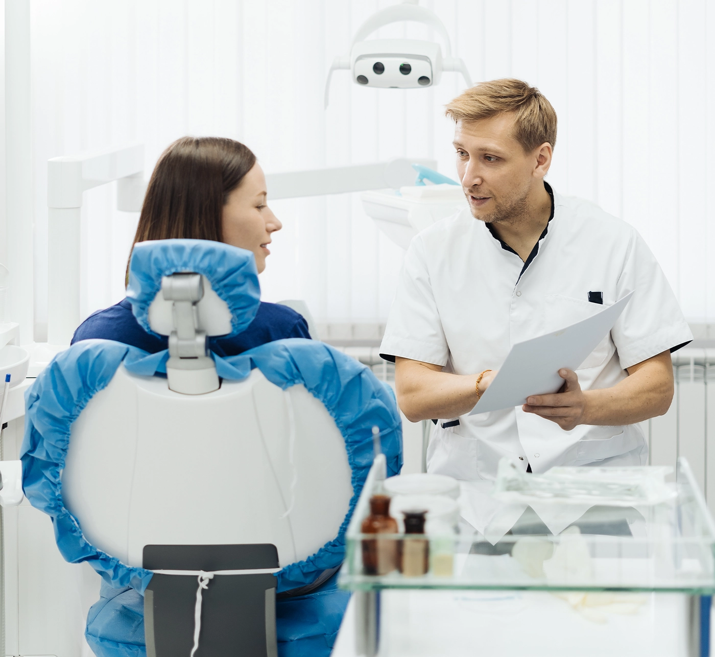 Male Professional Dentist With Gloves And Mask Holding papers photo And Show What The Treatment Will Look Like Of The Patient's Teeth. Discussion Of The Treatment Plan And Healthy Smile
