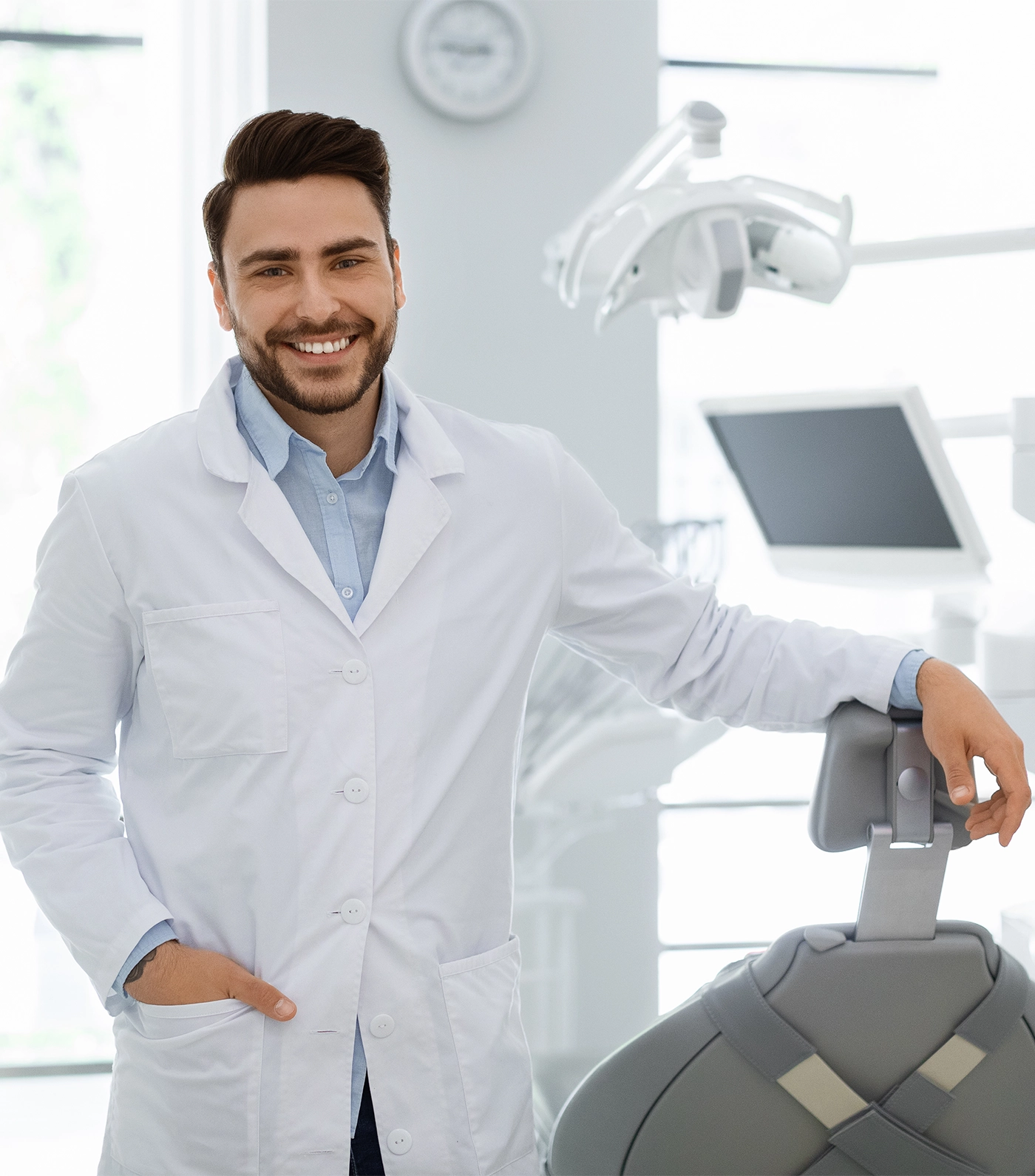 Handsome caucasian young man doctor posing at newest dental clinic, copy space. Happy bearded male dentist greeting patients or inviting to visit brand new modern dental clinic, healthcare concept