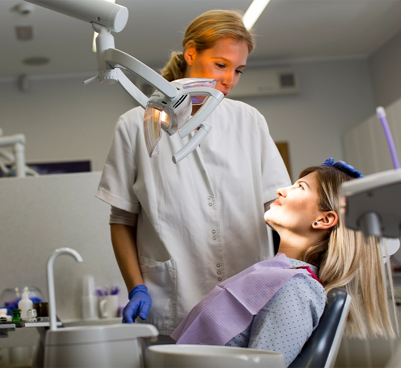 Doctor in uniform checking up female patient's teeth in dental clinic