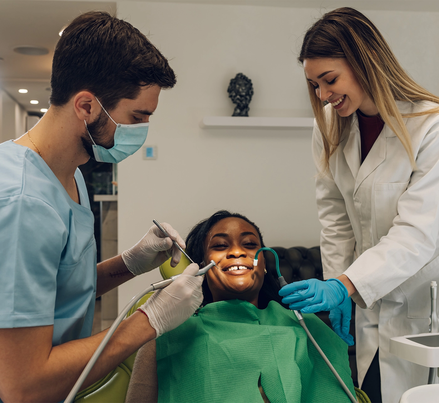 dentist providing oral care treatment and medical service to a african american female patient. Dental checkup at dental clinic. Assistant helping doctor with a procedure.