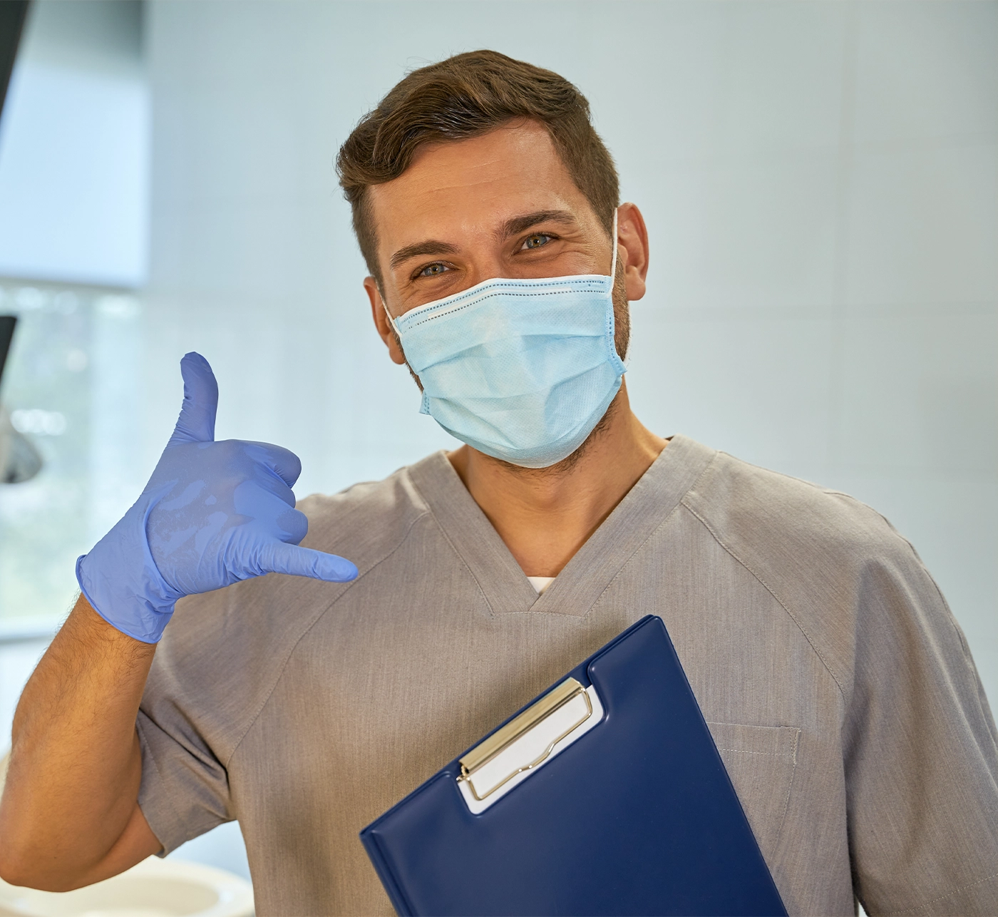 Male medical doctor in a mask holding hand and making gesture while standing at clinic