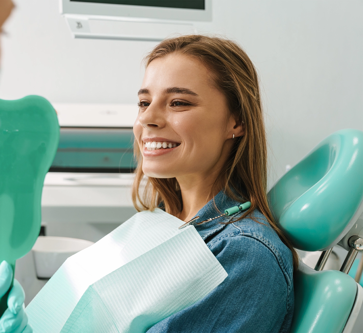 young woman smiling while looking at mirror in dental clinic